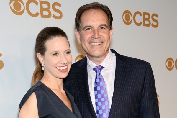Jim Nantz posing with his wife by wearing black suit.
